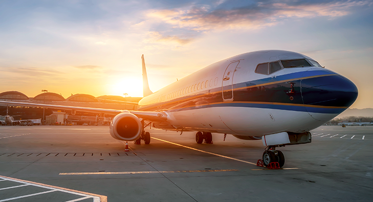 AMNS Applications & Marquee Projects: A sunset view of a sizable airplane parked on the tarmac.